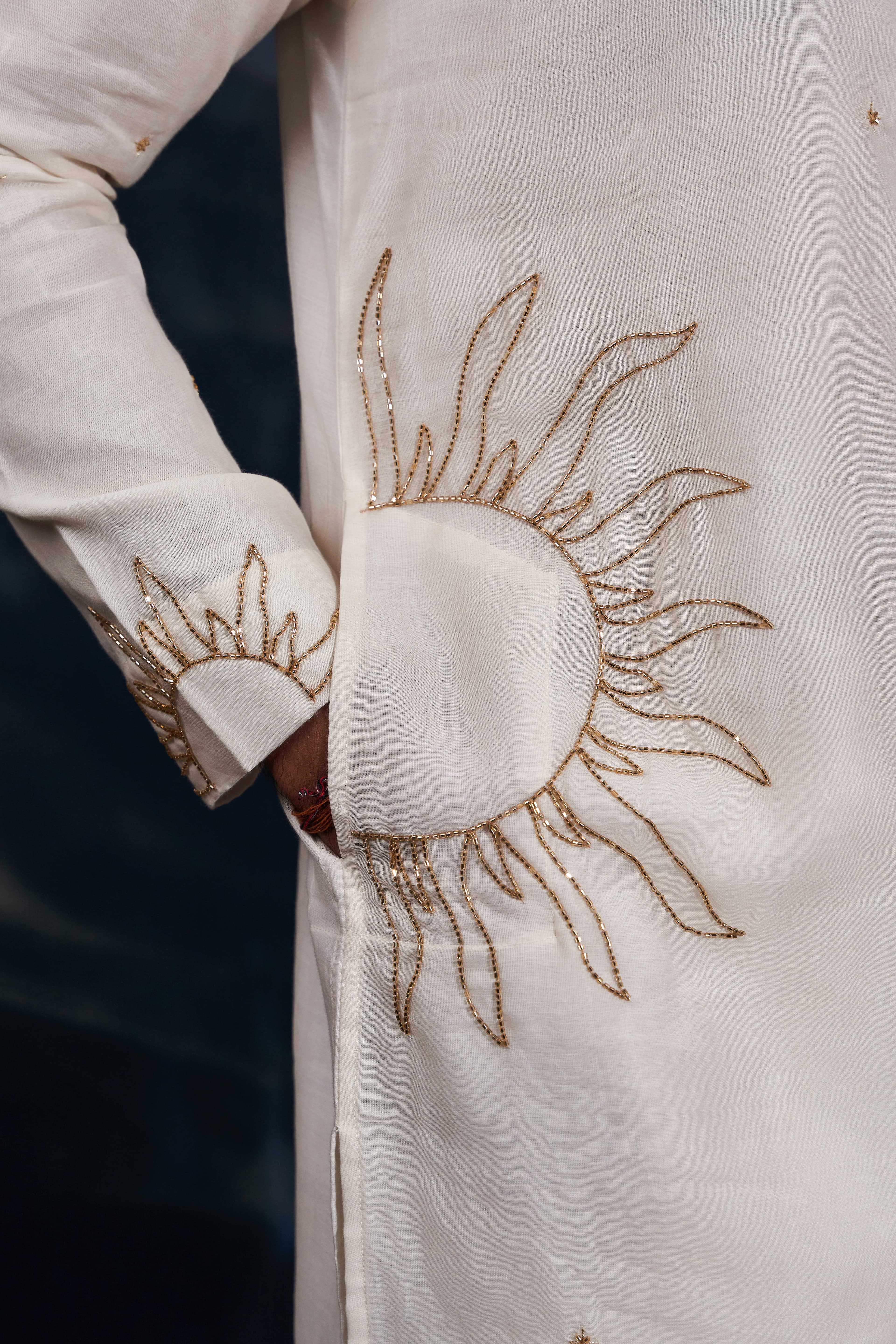 Close-up of a woman's neck showing a gold pendant necklace on a white blouse.